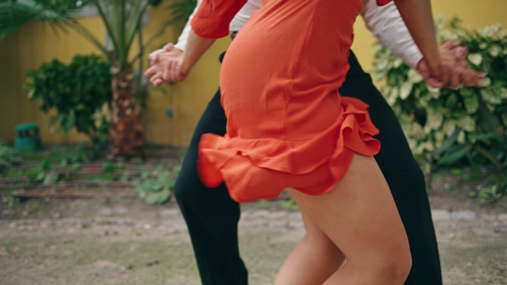 Young street dancers moving seductively in town park. View energetic woman hips